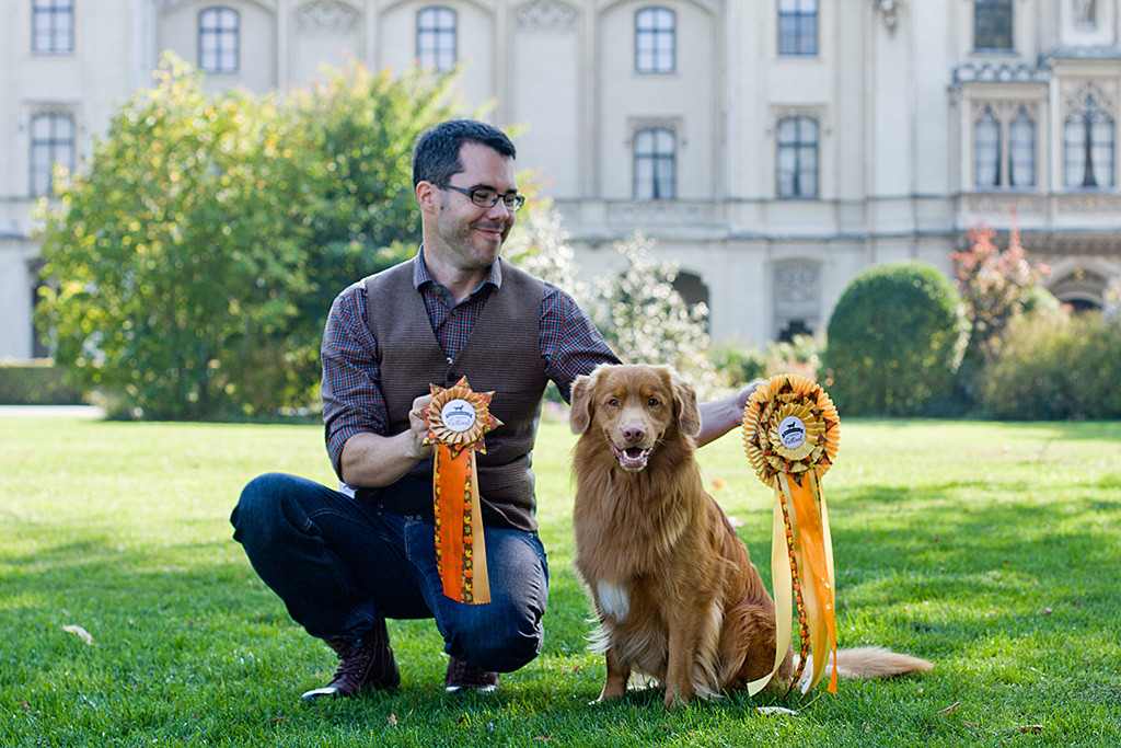 Edison sitzt neben Stephan, der kniend die BOB- und CACA-Schleife hält
