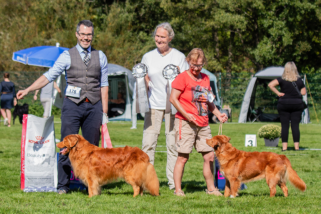 Edison posiert mit der Hündin fürs Siegerfoto, dahinter stehen ihre Besitzerin, die Richterin und Stephan