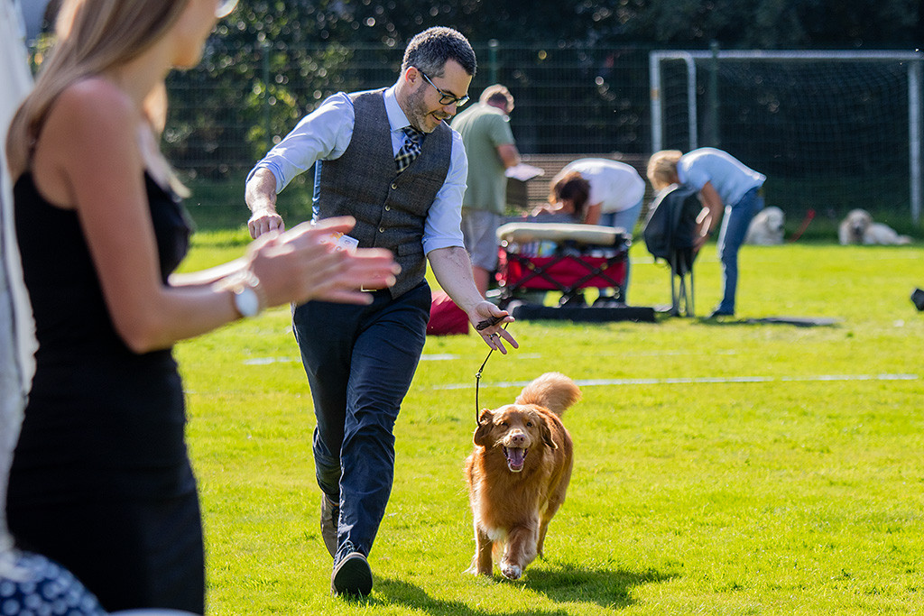 Edison läuft bei Applaus freudestrahlend mit weit geöffnetem Maul an Stephans Seite durch den Ring