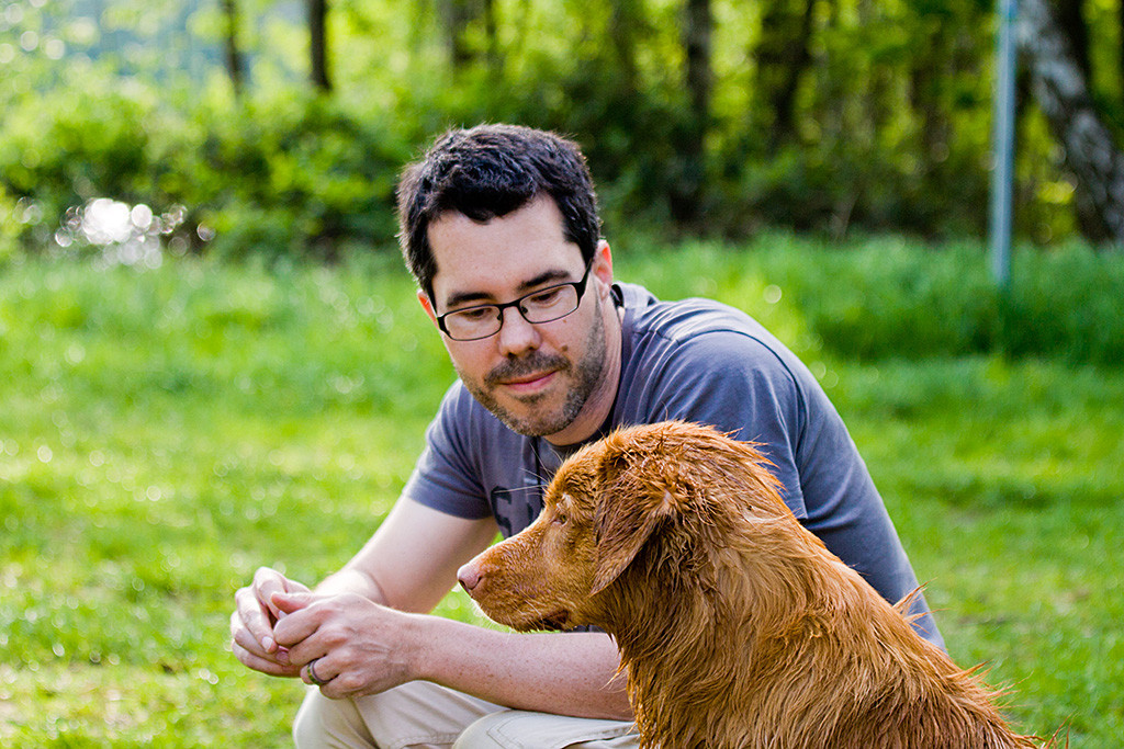 Edison sitzt während Stephan ihn lächelnd hockend anschaut