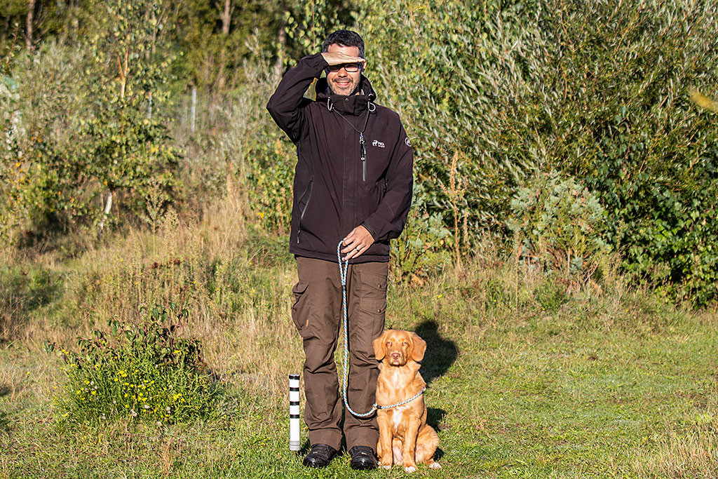 Newton sitzt angeleint neben Stephan, beide schauen nach vorn