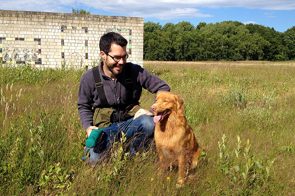 Edison sitzt im Gras, Stephan hockt neben ihn, beide lächeln zufrieden