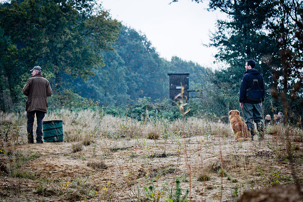 Edison sitzt angeleint neben Stephan, links von ihnen steht der Richter, im Hintergrund stehen Leute, die ein Treiben simulieren werden