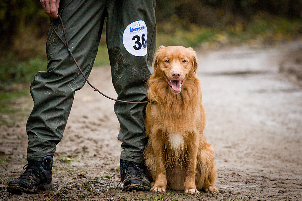 Edison sitzt angeleint neben Stephan und lächelt frontal in die Kamera