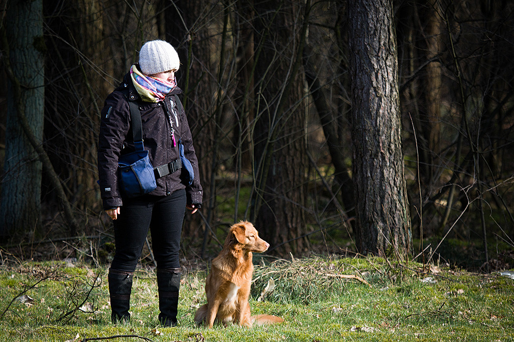 Carina steht auf der Wiese, daneben sitzt Ivalu, beide schauen nach rechts