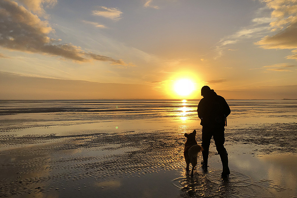 Edison läuft an Stephans Seite am Strand in den Sonnenuntergang