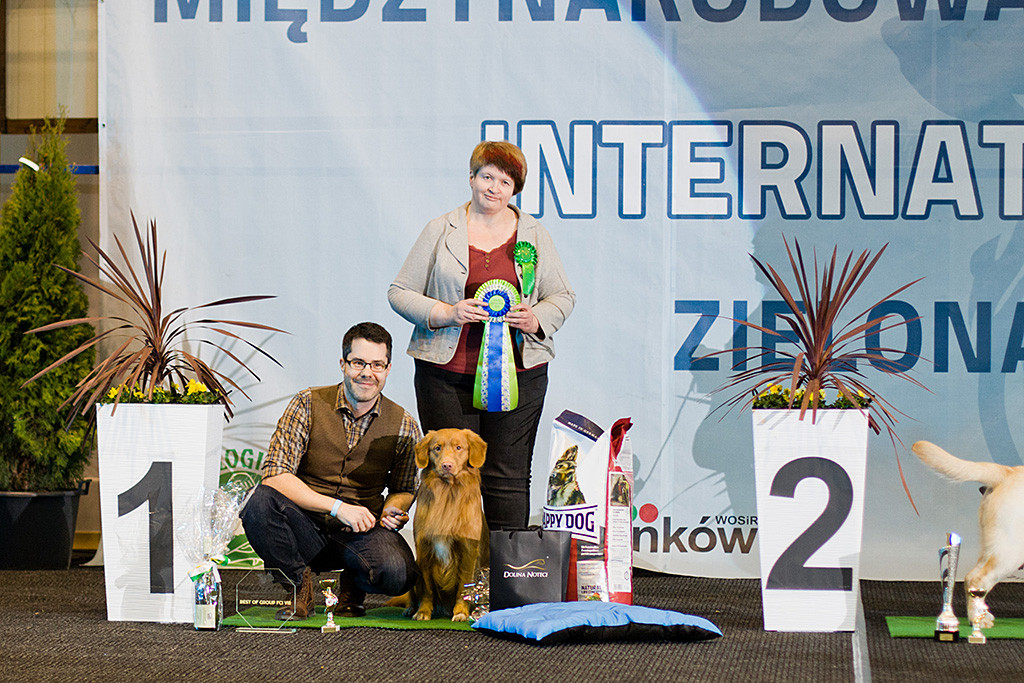 Edison sitzt neben Stephan, der an seiner Seite hockt, davor stehen seine Preise, dahinter die Richterin mit der Siegesschleife in der Hand