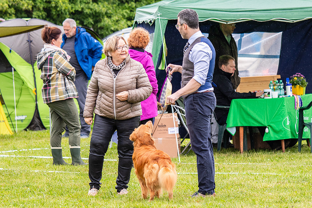 Newton steht zwischen Stephan und der Richterin, die ihm die Siegerschleife überreicht hat