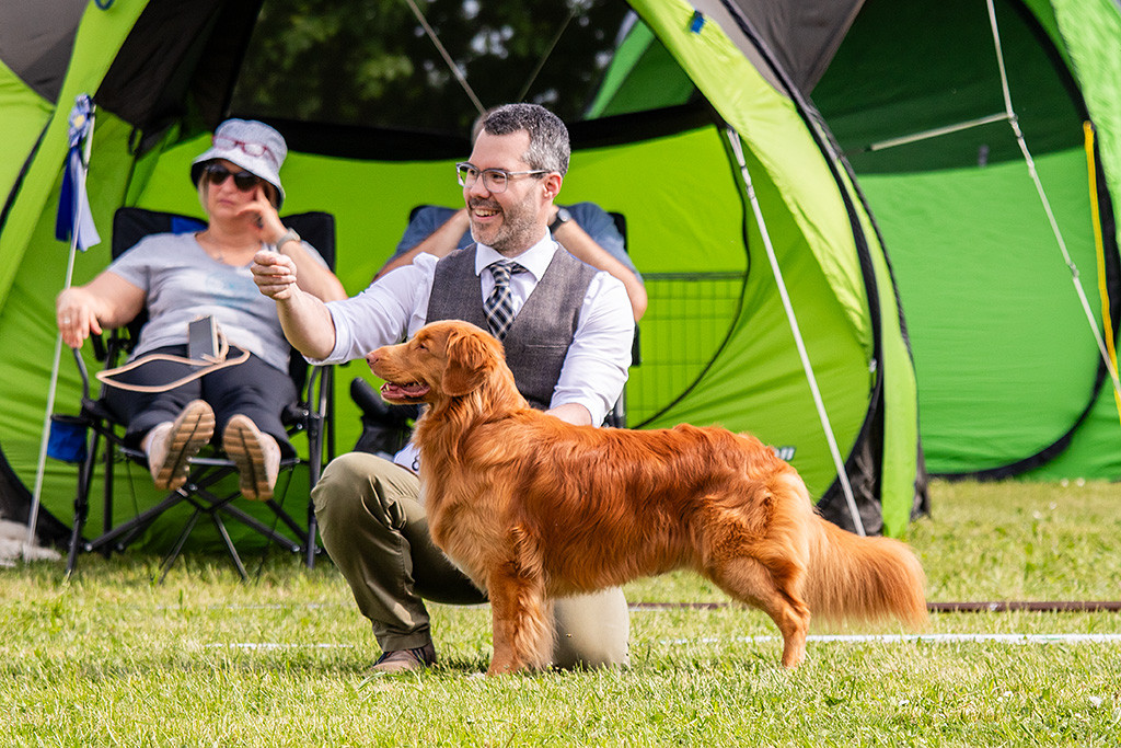 Newton steht seitlich im Profil und lächelt dabei, Stephan kniet dahinter